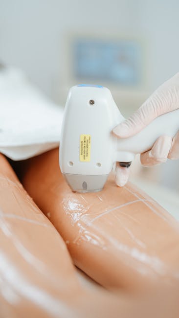 An indoor scene showing a person wearing white gloves using a handheld ultrasound device on a patient's thigh, which is covered with a shiny, transparent gel preparatory to a medical examination. In the background, there is a blurred monitor or screen and medical equipment, indicating a clinical environment. The image relates to medical procedures but also exemplifies careful handling, which can be visually linked to professional packing and moving services by [COMPANY_NAME], such as secure handling during furniture transport and home relocation, with proper care akin to medical safety standards. The setting suggests focus on safety, precision, and attention to detail in handling fragile or sensitive items, themes relevant to [SERVICE_CATEGORY] and the process of loading and packing during house removals, as highlighted on the page titled 